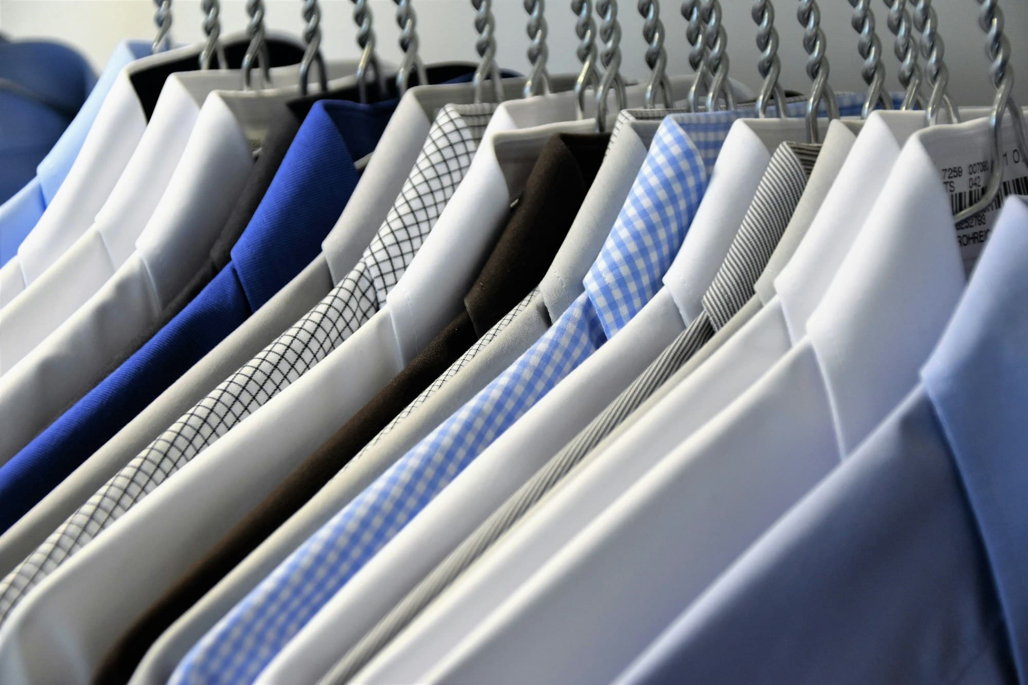 Freshly laundered shirts hanging in a row, pressed and ready